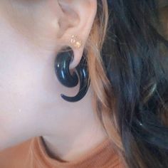 a close up of a person wearing large black earrings