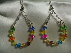 two pairs of earrings with colorful beads hanging from them on a white fabric background,