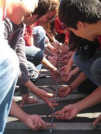 a group of people sitting on the ground with their hands together and reaching for something