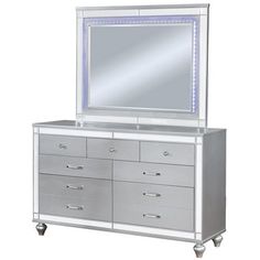 a silver dresser with a mirror and lights on the bottom shelf, along with drawers