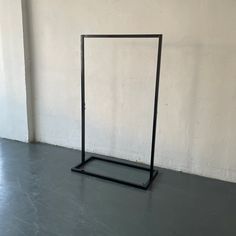 a black metal frame sitting on top of a cement floor next to a white wall