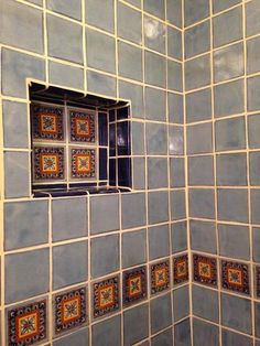 a bathroom with blue and orange tiles on the shower wall, window in the corner