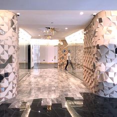 a man is walking through an office lobby with black and white tiles on the walls