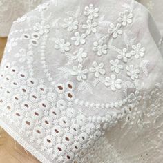 white lace with flowers on it sitting on top of a wooden table