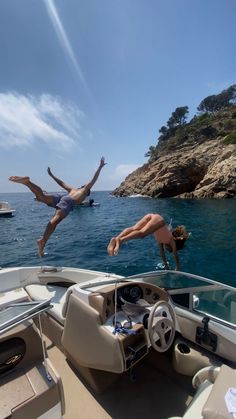 two people diving into the water from a boat