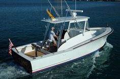 a man driving a boat in the water with an american flag on it's side