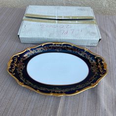 a blue and gold plate sitting on top of a table next to a white box