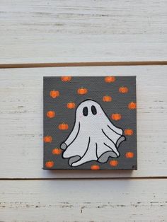 a painting of a ghost with pumpkins around it on a white wooden surface,