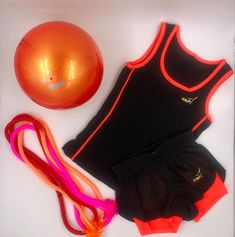 an orange ball, black top and pink shorts are next to a pair of exercise equipment