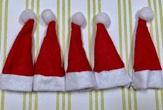 four red and white santa hats sitting on top of a striped tablecloth with yellow stripes