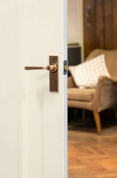 an open door with a handle on it in front of a living room chair and couch