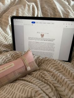 an open laptop computer sitting on top of a bed next to a pillow and pillow case