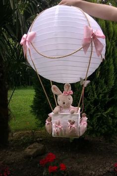 a stuffed bunny in a basket with pink bows on it being lifted by a person