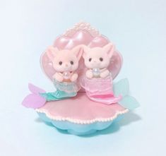 two little pigs sitting on top of a pink heart shaped object with pearls around their necks