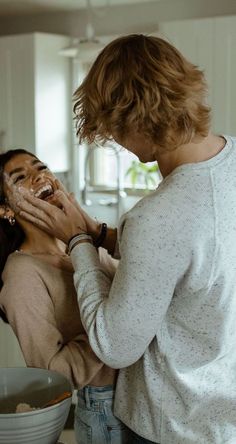 two women are standing in the kitchen and one is holding her face up to her mouth