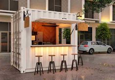 an outdoor bar made out of shipping containers with stools in front of it at dusk