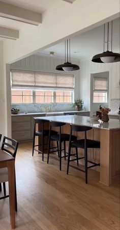 an open kitchen and dining room with wooden floors, white walls, and gray cabinets