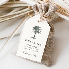 a welcome tag with a palm tree is tied to a burlocked bag