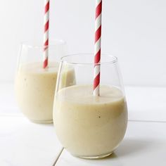 two glasses filled with smoothie sitting on top of a white counter next to each other