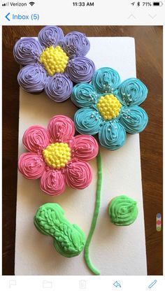 three flowers made out of fondant sitting on top of a piece of paper