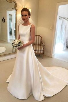 a woman standing in front of a mirror wearing a white dress and holding a bouquet