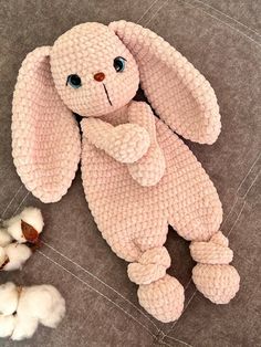 a pink stuffed animal sitting on top of a gray floor next to cotton floss