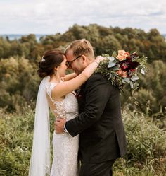 a bride and groom embracing each other in front of trees