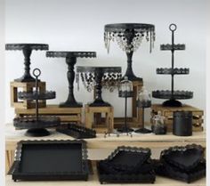 a table topped with lots of black vases and candlesticks on top of wooden boxes