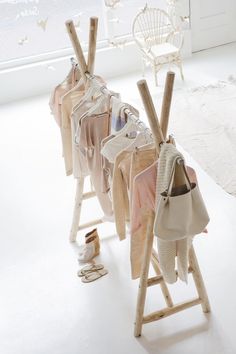 an image of clothes hanging on a rack in the middle of a room with white walls