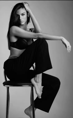 a woman sitting on top of a chair in black and white posing for the camera