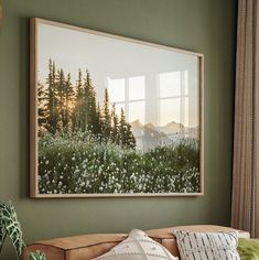 a painting hanging on the wall above a couch in a room with green walls and pillows