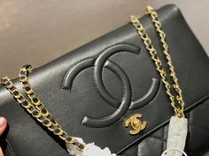 a person holding a black purse with gold chains