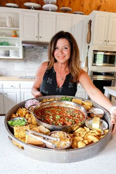 a woman holding a large metal pan filled with food