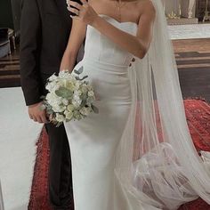 a man and woman standing next to each other in front of a wedding arch with flowers on it