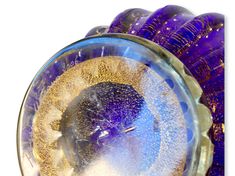 a close up of a purple and gold object in a glass bowl on a white background