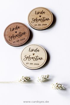 three personalized wooden magnets sitting on top of a white table next to flowers