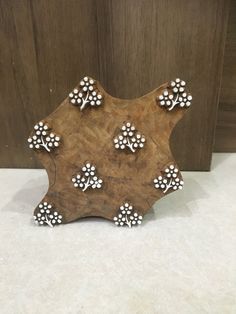 a wooden object with white dots on it sitting on a table next to a wall