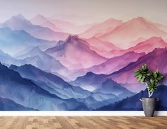 a large wall mural with mountains painted on it's sides and a potted plant in the foreground