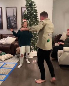 a man and woman dancing in front of a christmas tree