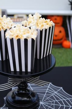 black and white striped cupcakes sitting on top of a cake plate with spider web decorations