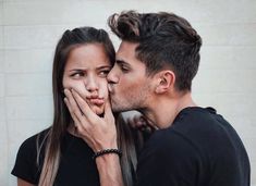 a man kissing a woman's face with his hand on her cheek, while she is