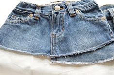 a pair of blue jean shorts sitting on top of a white bed sheet with buttons