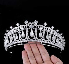 a hand holding a tiara with pearls and diamonds