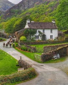 a white house sitting on the side of a road next to a lush green hillside