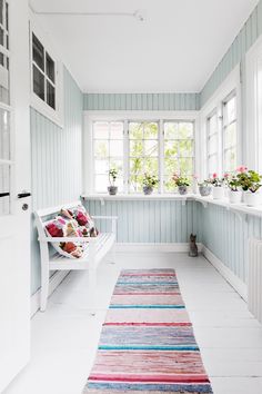 a white hallway with blue walls and striped rug