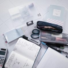 an open notebook sitting on top of a table next to a calculator and pen