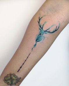 a tattoo on the arm of a person with a deer head and arrow