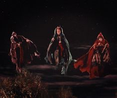 three women dressed in red and black are walking through the night sky with their hands on their hips