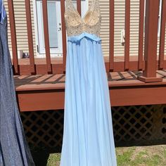 a dress hanging on a clothes line in front of a wooden porch with a house behind it