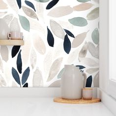 a white counter top sitting next to a wall with leaves painted on the side of it